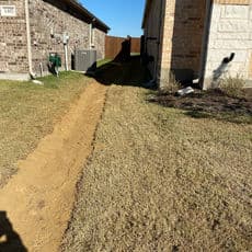 Path between two houses leading to a wooden fence, with utilities visible on the left side.