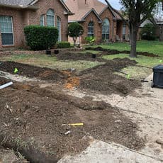 Residential yard excavation for landscaping project with marked areas and equipment.