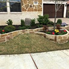 Landscape garden with curved stone border, vibrant flowers, and neatly trimmed grass.