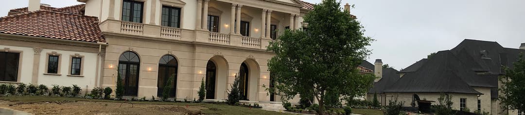 Luxury estate with Mediterranean architecture, large windows, and lush landscaping.