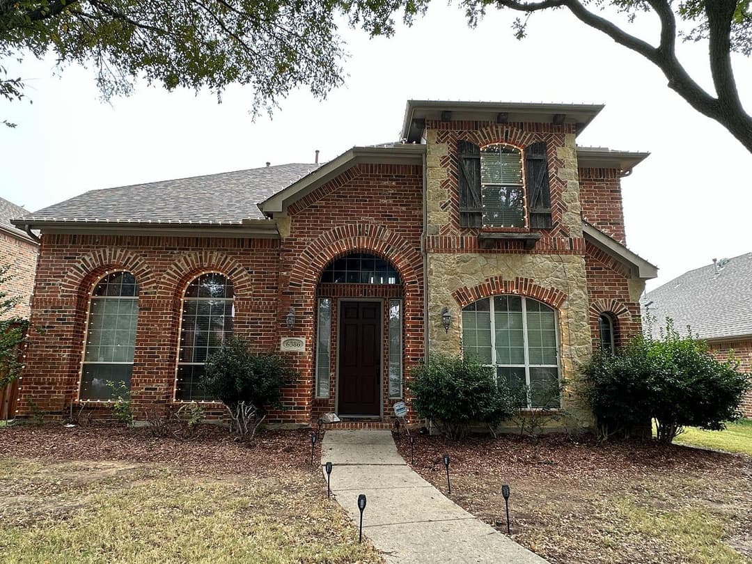 Brick home with stone accents, large windows, and a landscaped front yard. Ideal family residence.