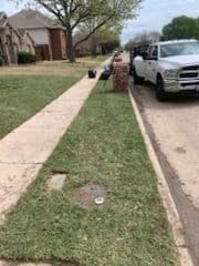 Clean suburban sidewalk with grass, a residential house, and a parked white truck.