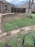 Home lawn renovation with freshly laid sod and a person working in the yard.