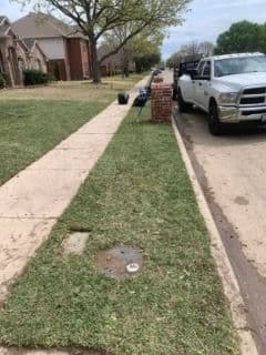 Lawn maintenance in a residential area with freshly cut grass and parked vehicles.