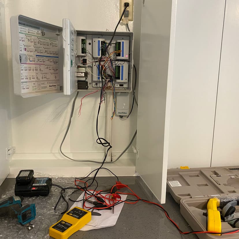 Electrical control panel with exposed wiring and tools on a work surface.